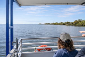 Guests watching the Banana River Lagoon from the rail of a Cocoa Beach Eco Tours pontoon boat