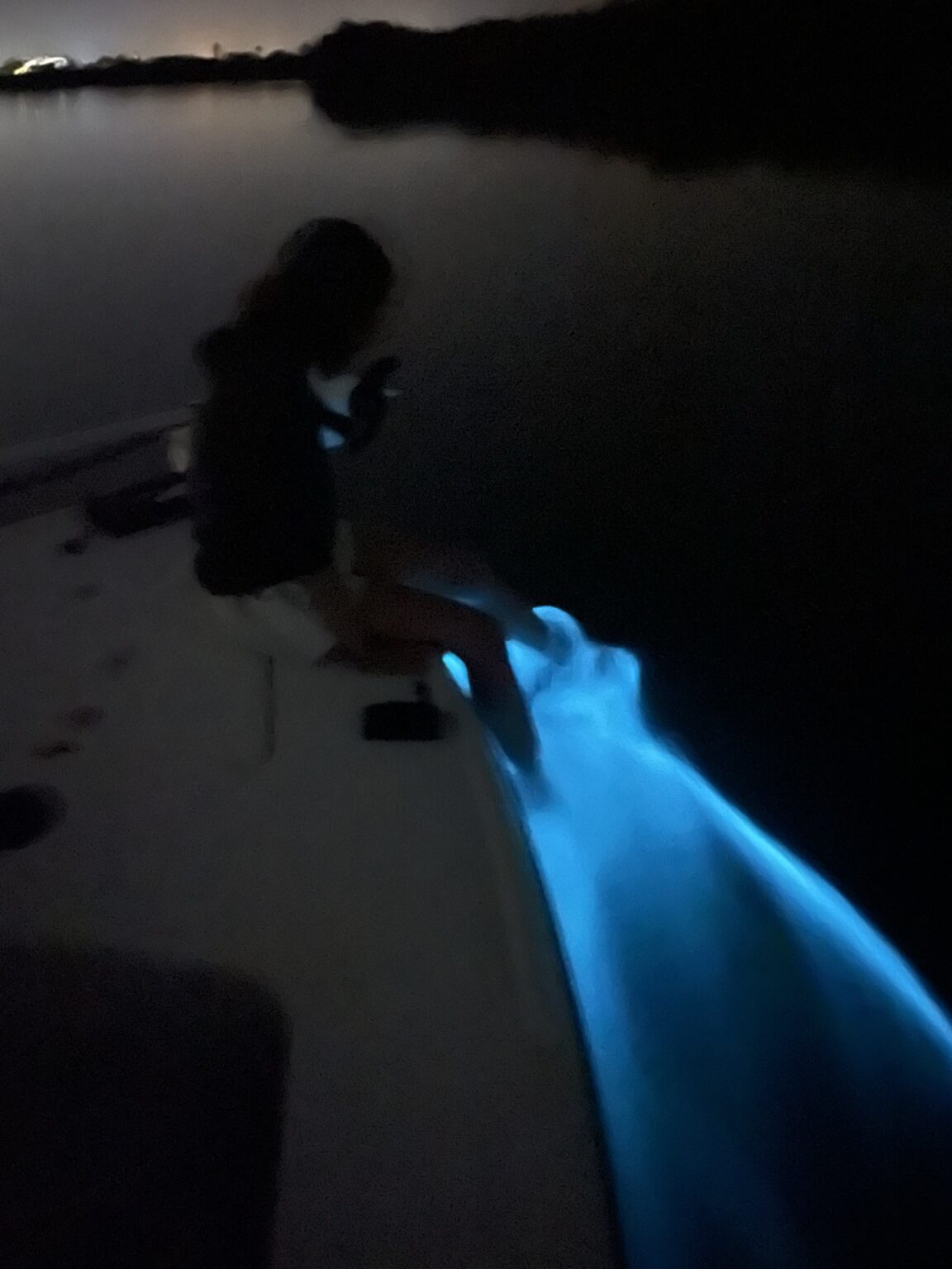 Bioluminescent water glowing blue beside a boat on the Banana River Lagoon at night