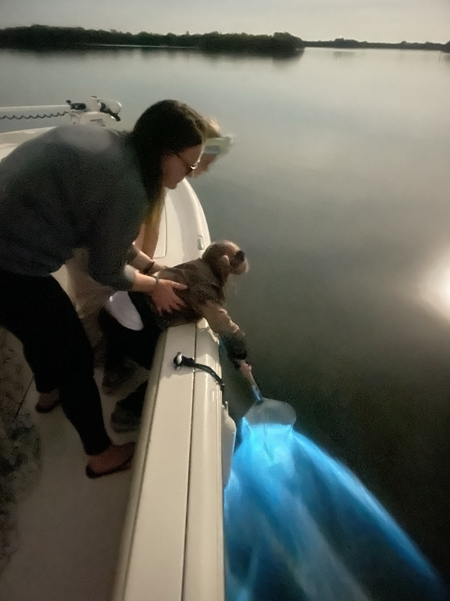 Guests trailing a net through glowing water from a boat on the Banana River Lagoon at dusk