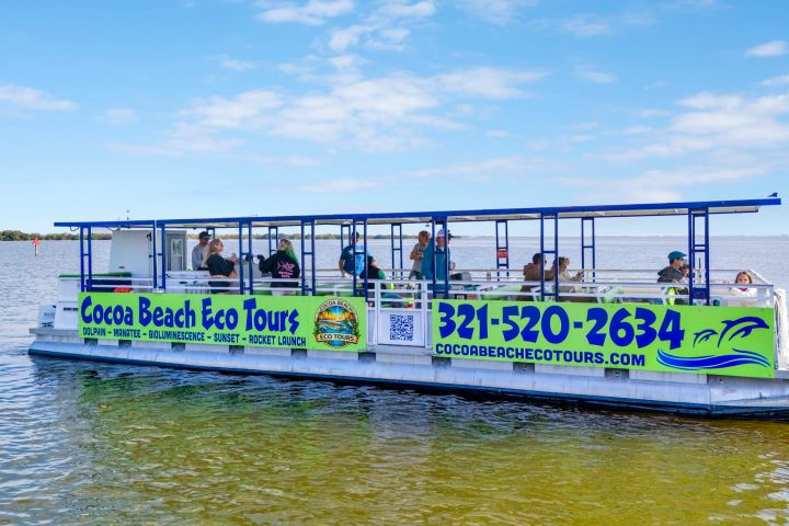 Tour boat on water with signs for Cocoa Beach Eco Tours and contact info next to passengers.