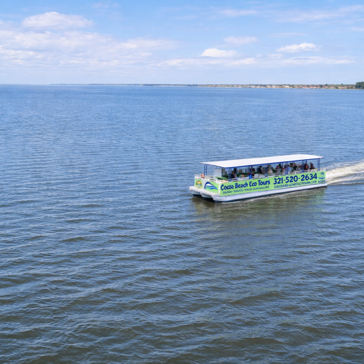 Tour boat with passengers on a calm lake under a cloudy sky.